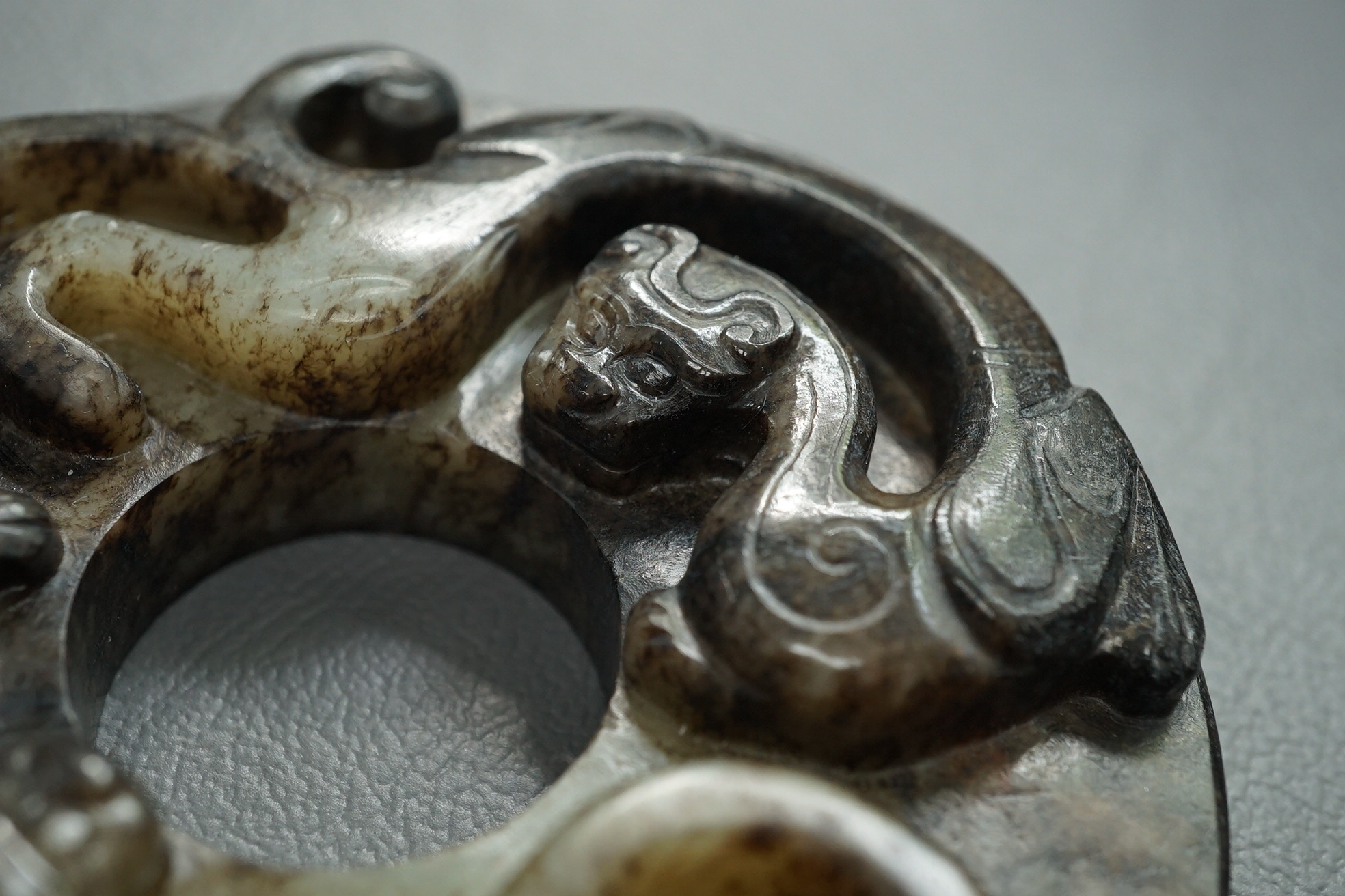 A Chinese pale celadon and black jade bi disc